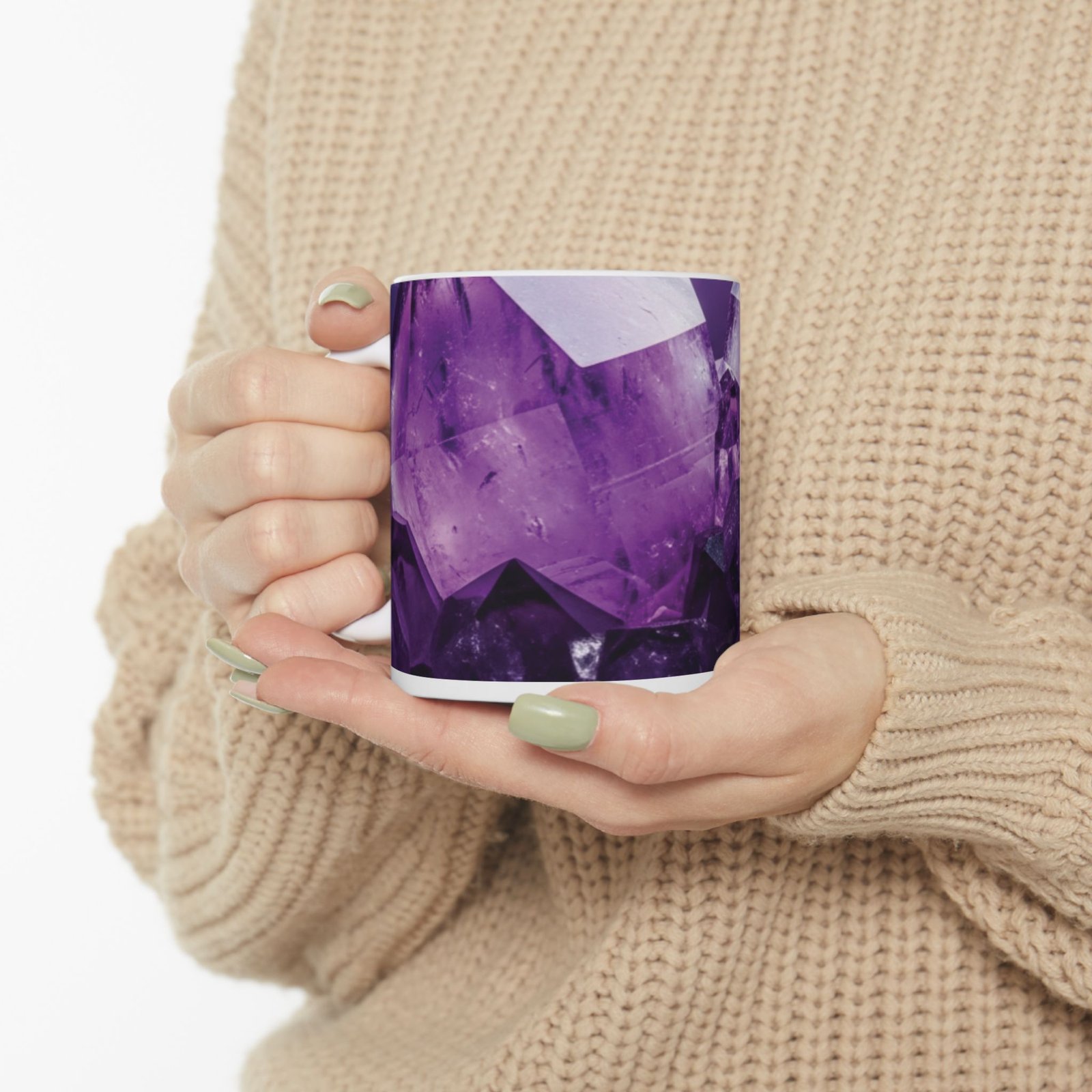 A person holding a glossy white ceramic mug featuring a vibrant, close-up amethyst crystal print with deep purple tones.