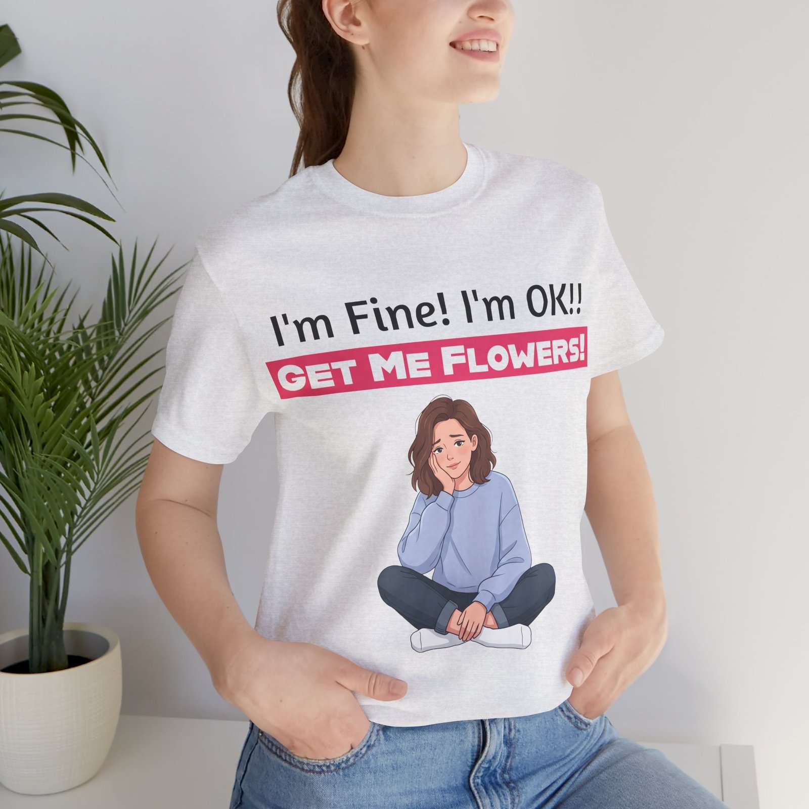 A person wearing a white t-shirt with 'I'm Fine! I'm OK!! GET ME FLOWERS!' text and a funny cartoon graphic.