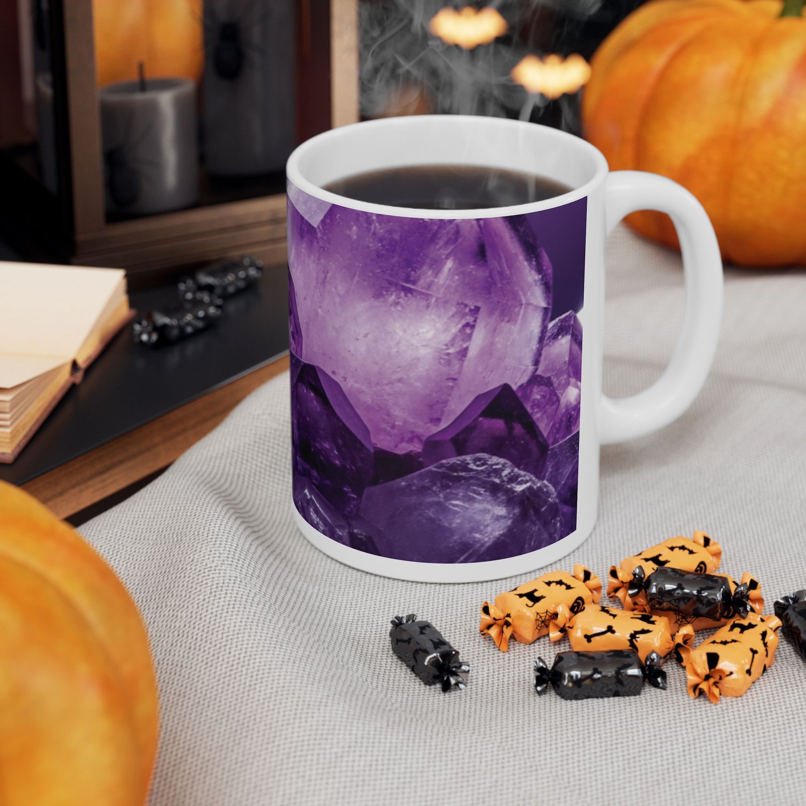 A white ceramic mug with a vivid purple amethyst crystal print filled with coffee, surrounded by pumpkins and candy.