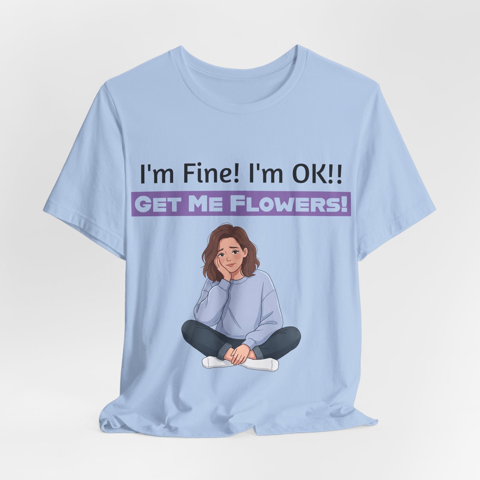 Light blue t-shirt featuring a cartoon woman sitting and reading "I'm Fine! I'm OK!! GET ME FLOWERS!" in purple text.