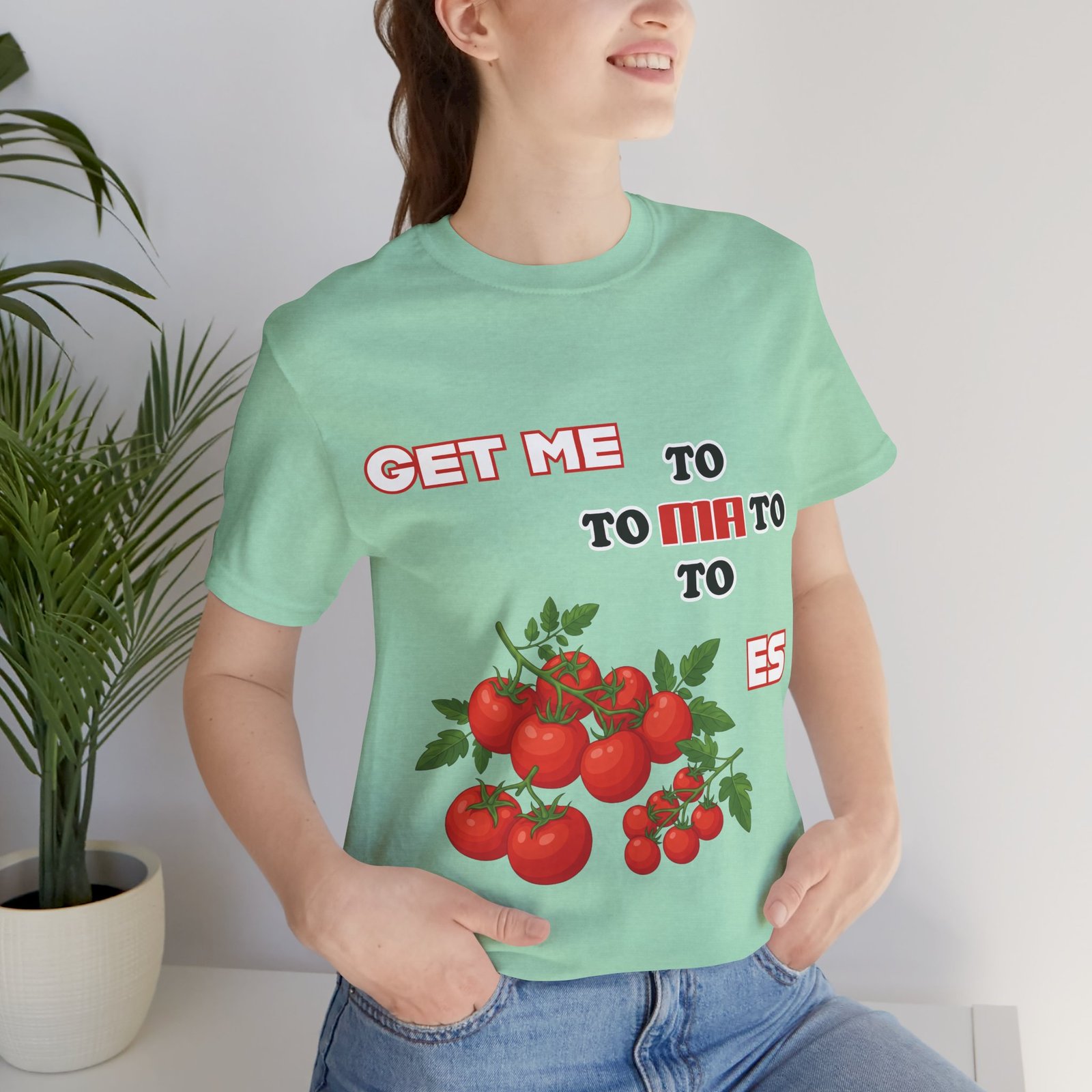 Light mint green t-shirt featuring a colorful illustration of fresh tomatoes and the fragmented text "Get Me To Ma To Toes".