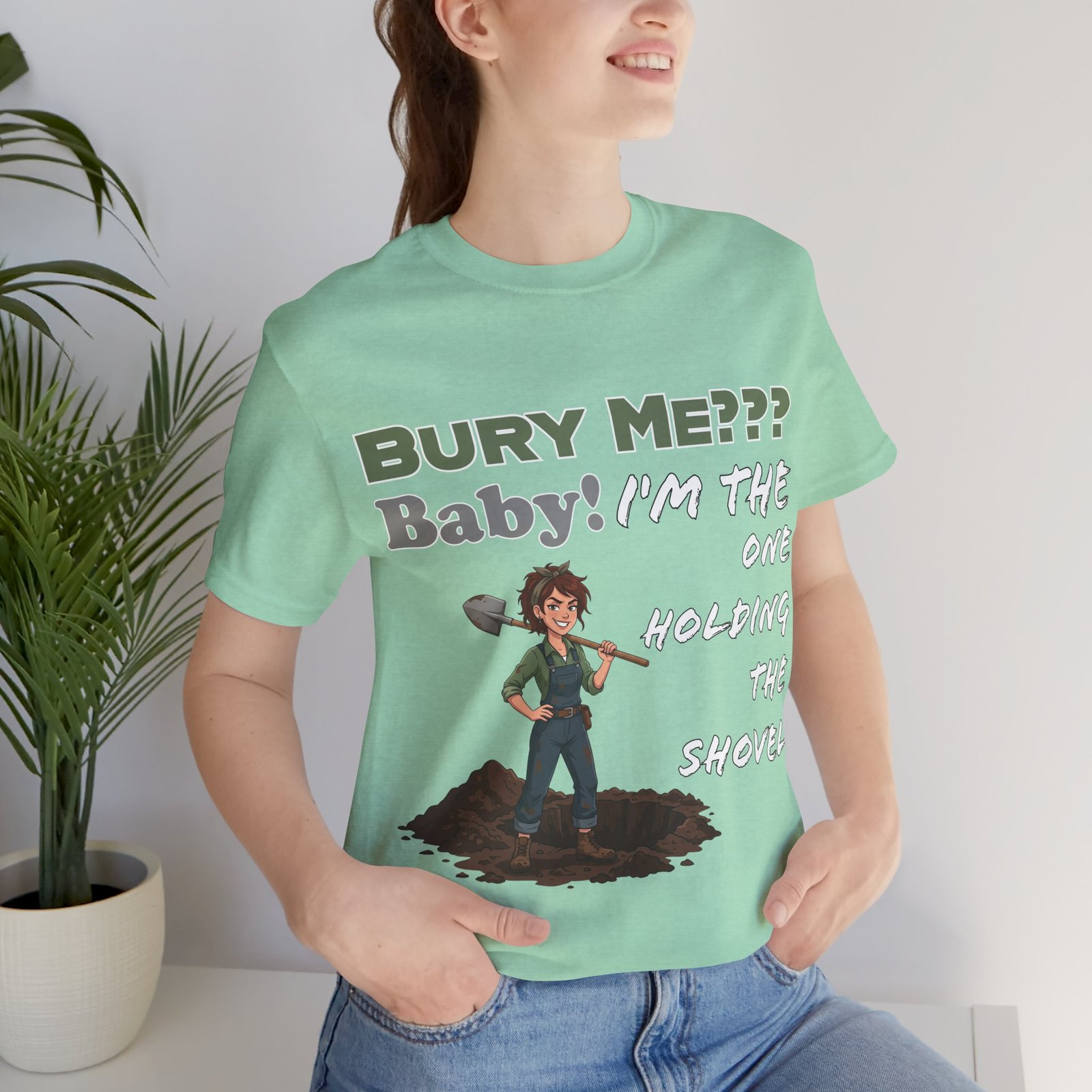 Mint green T-shirt featuring a dark humor illustration of a woman holding a shovel and the text BURY ME??? BABY!