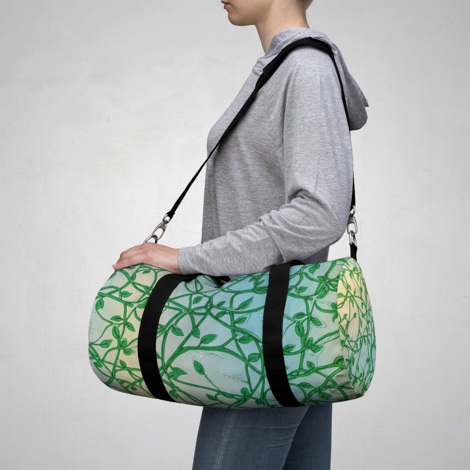 Person carrying a green vines pattern duffel bag with an adjustable shoulder strap and botanical design.