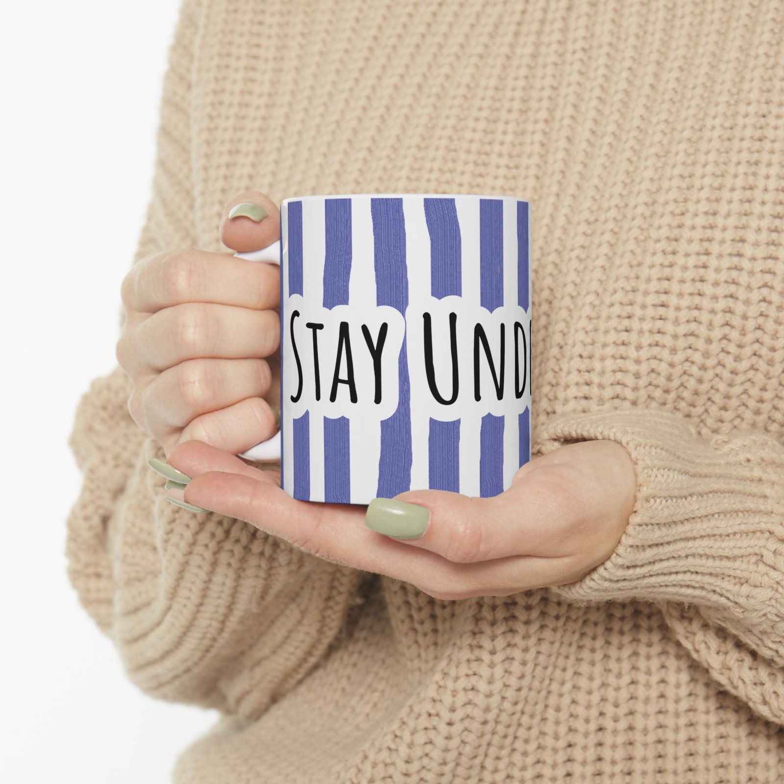 Person holding a periwinkle striped ceramic mug with hand-lettered 'Stay Under Blue' text.