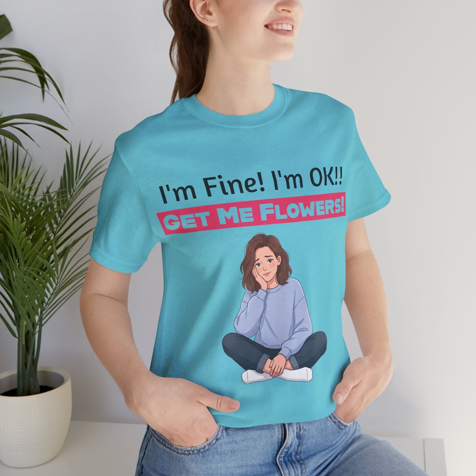 Person wearing a light blue funny T-shirt with the text 'I'm Fine! I'm OK!! GET ME FLOWERS!' and a cartoon graphic.