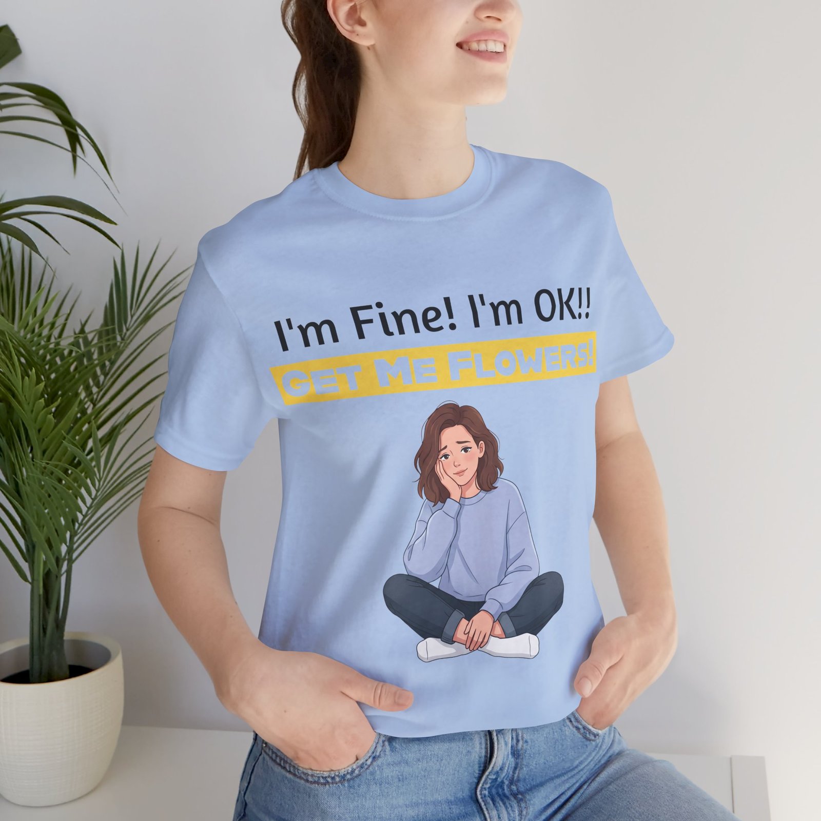 Person wearing a light blue 'I'm Fine! I'm OK!! Get Me Flowers!' t-shirt with a cartoon illustration of a girl.