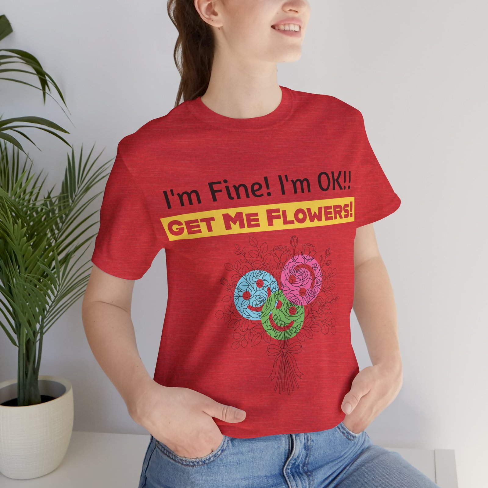 Person wearing a red crew-neck t-shirt with the text "I'm Fine! I'm OK!! GET ME FLOWERS!" and colorful floral graphic.