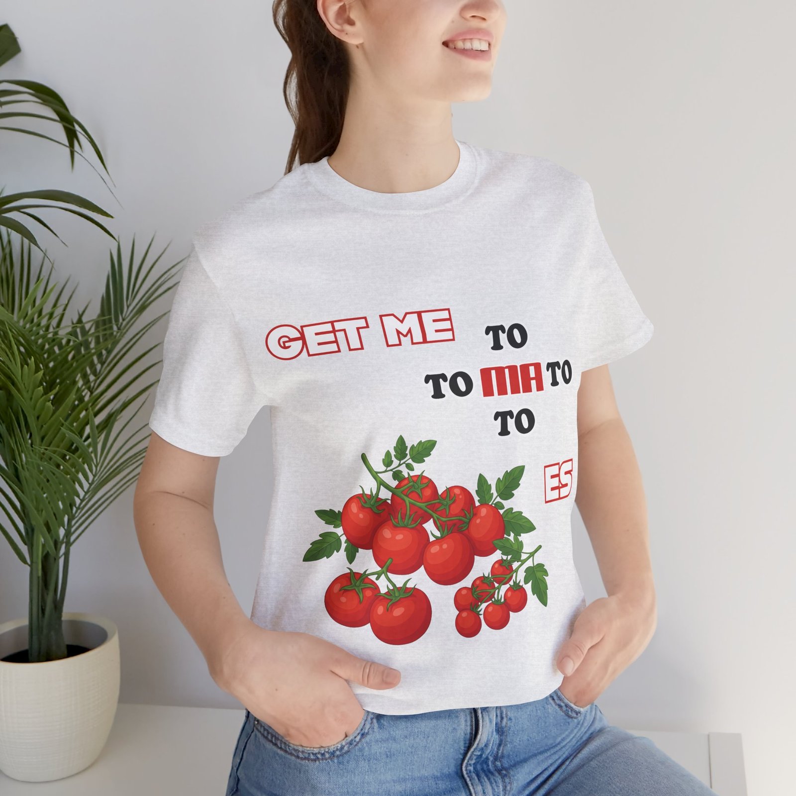 Person wearing a white Get Me To Ma To Toes T-shirt featuring red tomato illustrations and bold retro typography.