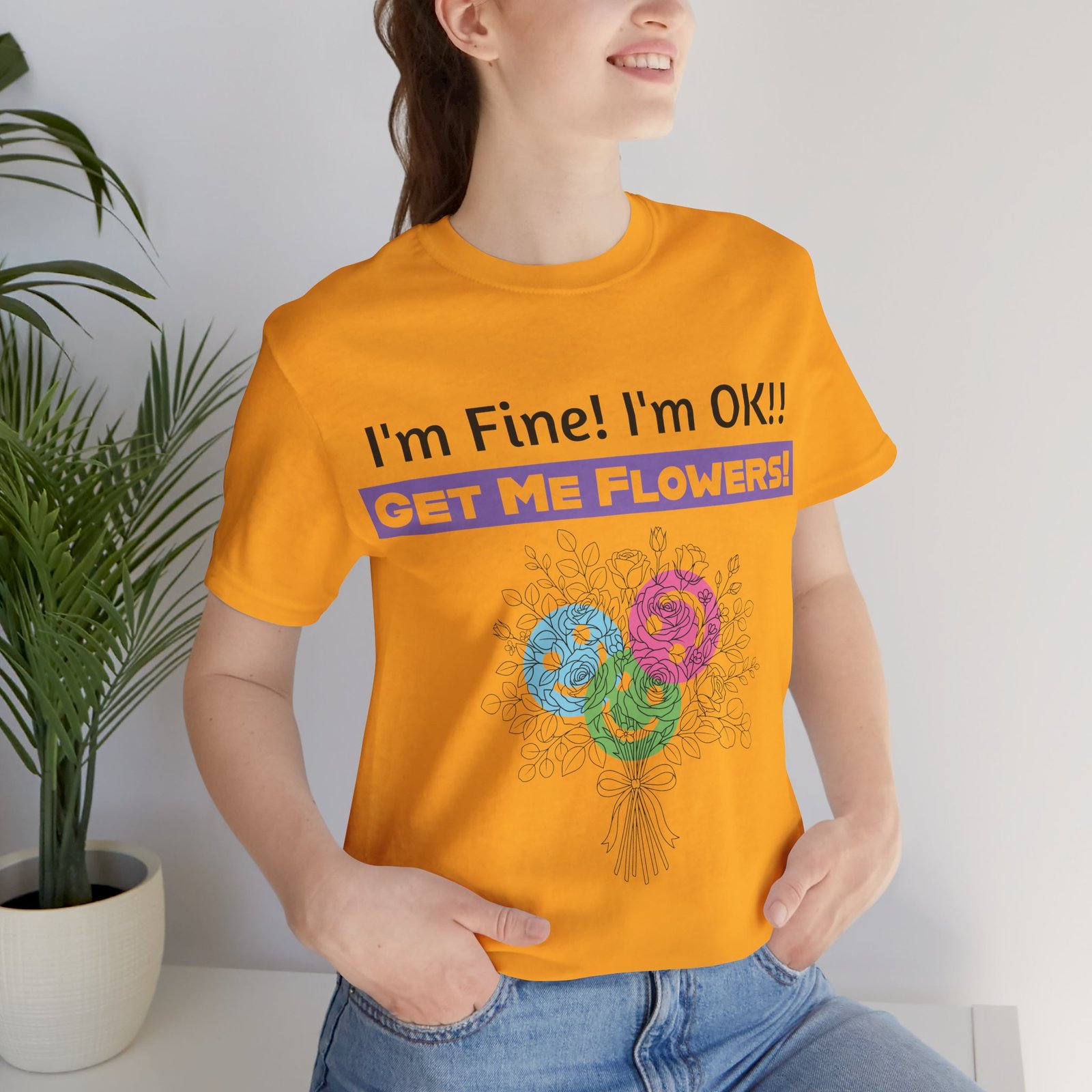 Person wearing an orange funny sarcastic floral graphic t-shirt that says I'm Fine! I'm OK!! GET ME FLOWERS!