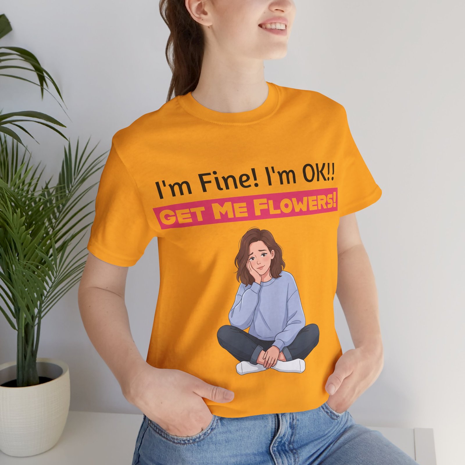 Person wearing an orange funny T-shirt with "I'm Fine! I'm OK!! GET ME FLOWERS!" text and a cartoon girl graphic.