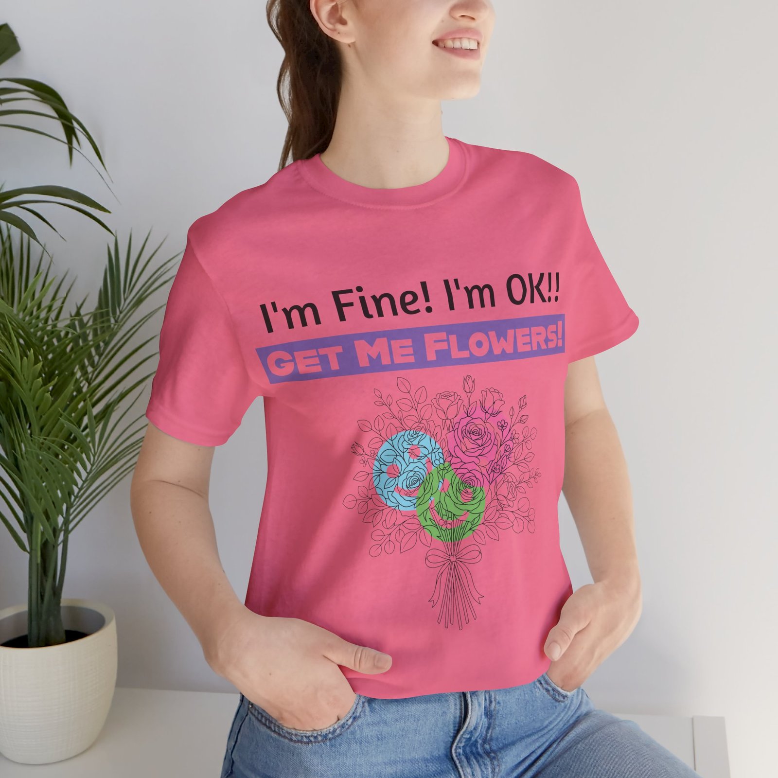 Pink graphic t-shirt featuring a sarcastic floral design with the text "I'm Fine! I'm OK!! Get Me Flowers!"