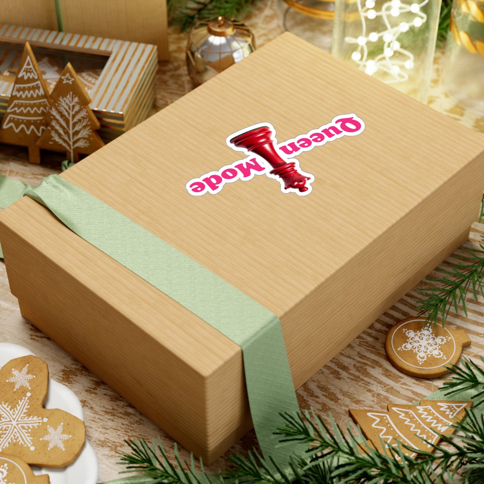 Queen Mode red chess queen sticker on a wooden gift box surrounded by gingerbread cookies and festive decorations.