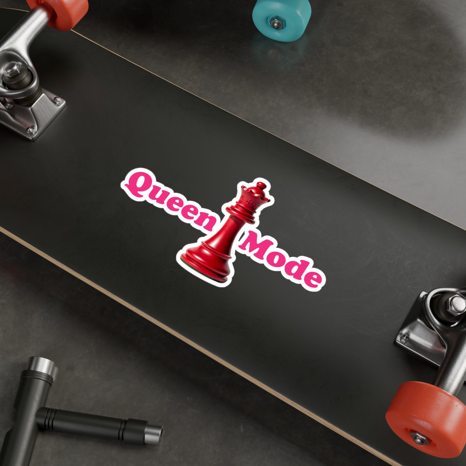 Queen Mode red chess queen sticker with bright pink text on a black skateboard