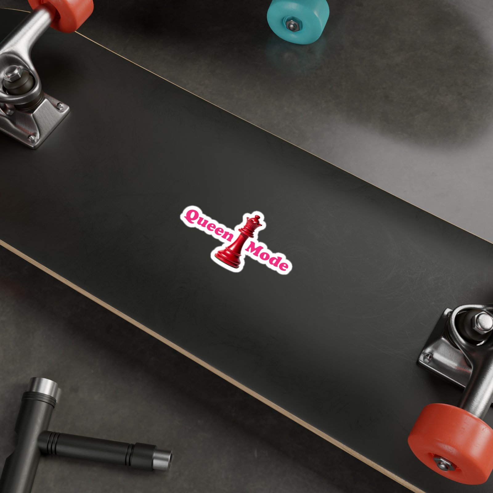 Queen Mode sticker featuring a red chess queen and bright pink text on a dark skateboard surface.