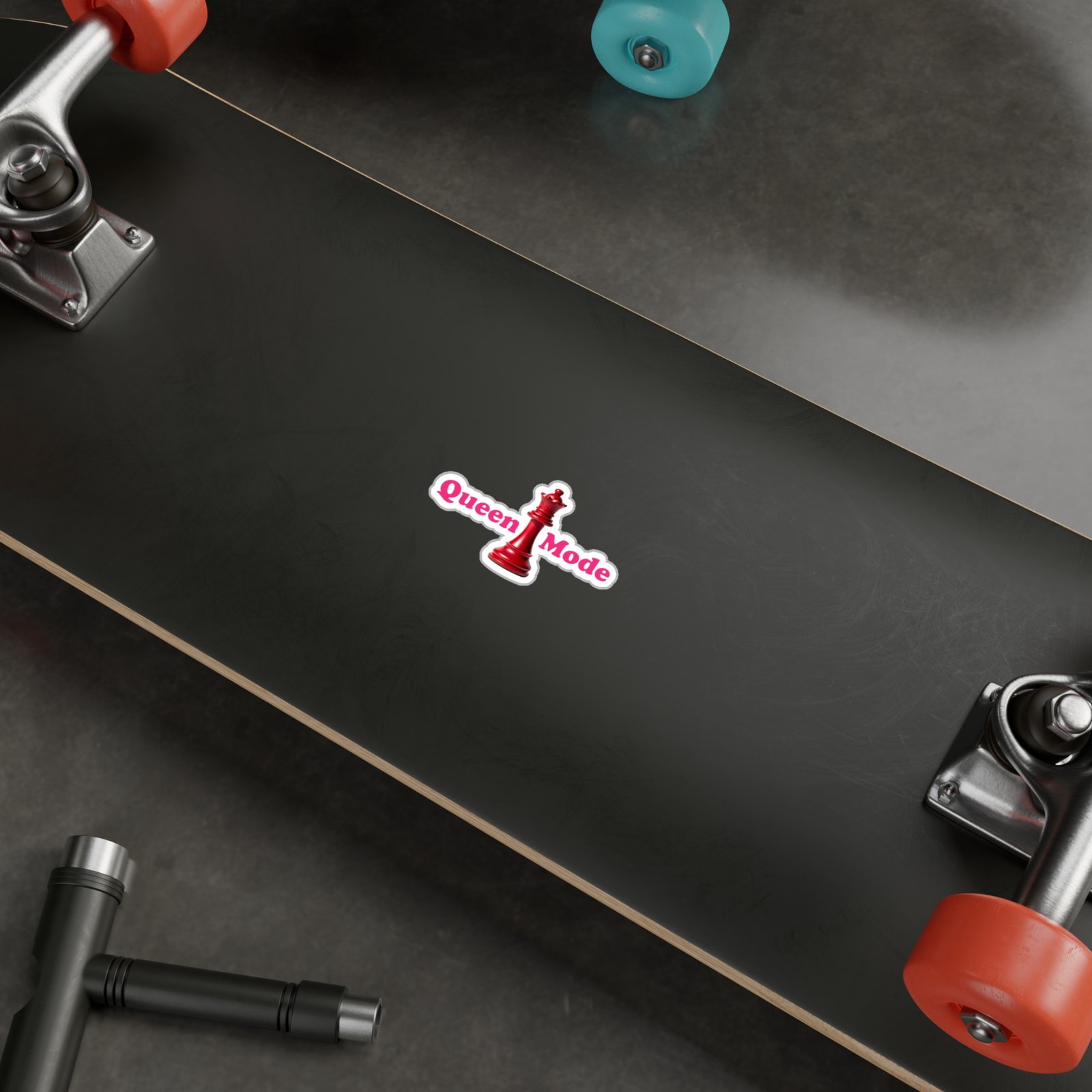 Queen Mode sticker with a red chess queen and pink text on a black skateboard deck.