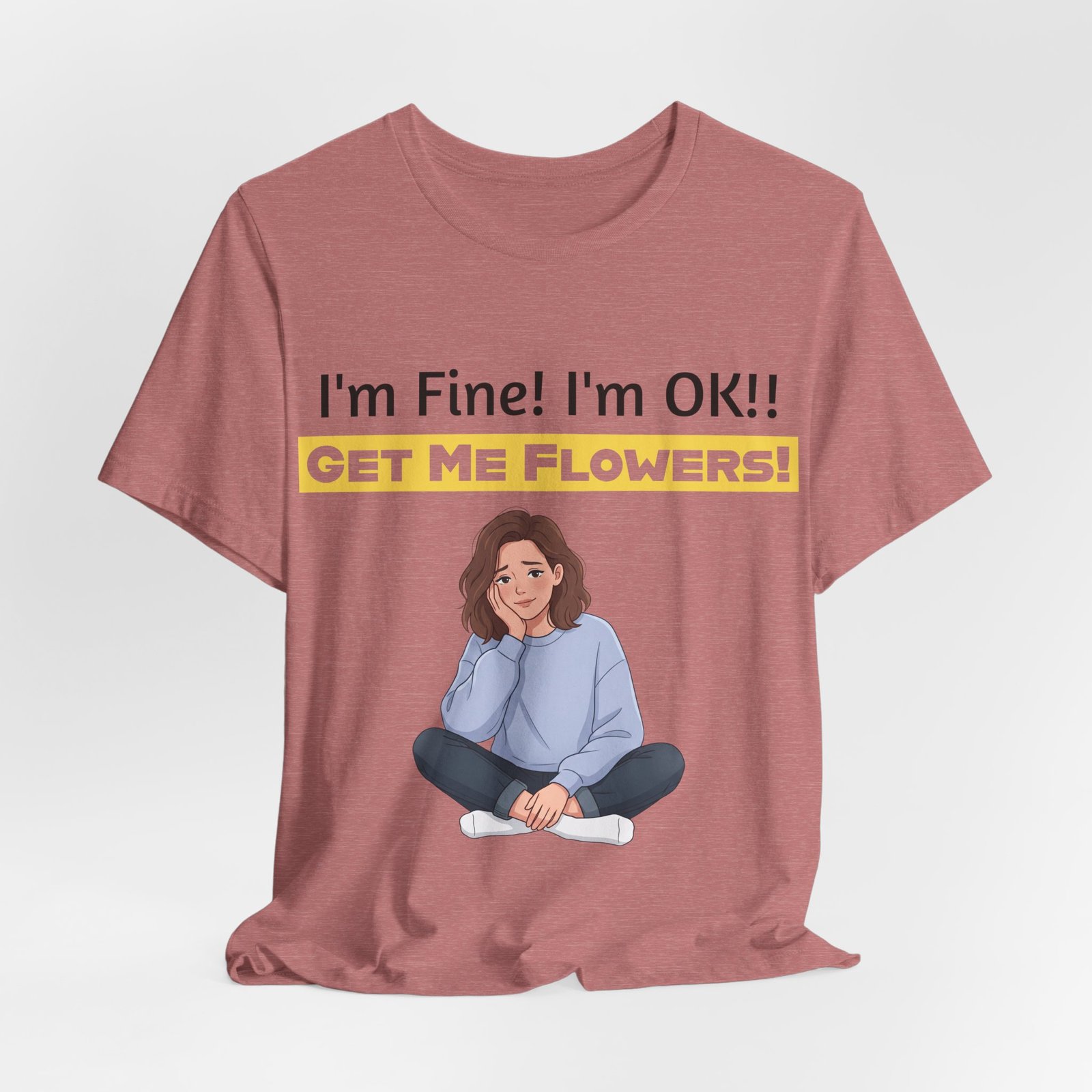 Rose-colored T-shirt featuring a cartoon woman sitting and the text I'm Fine! I'm OK!! Get Me Flowers!