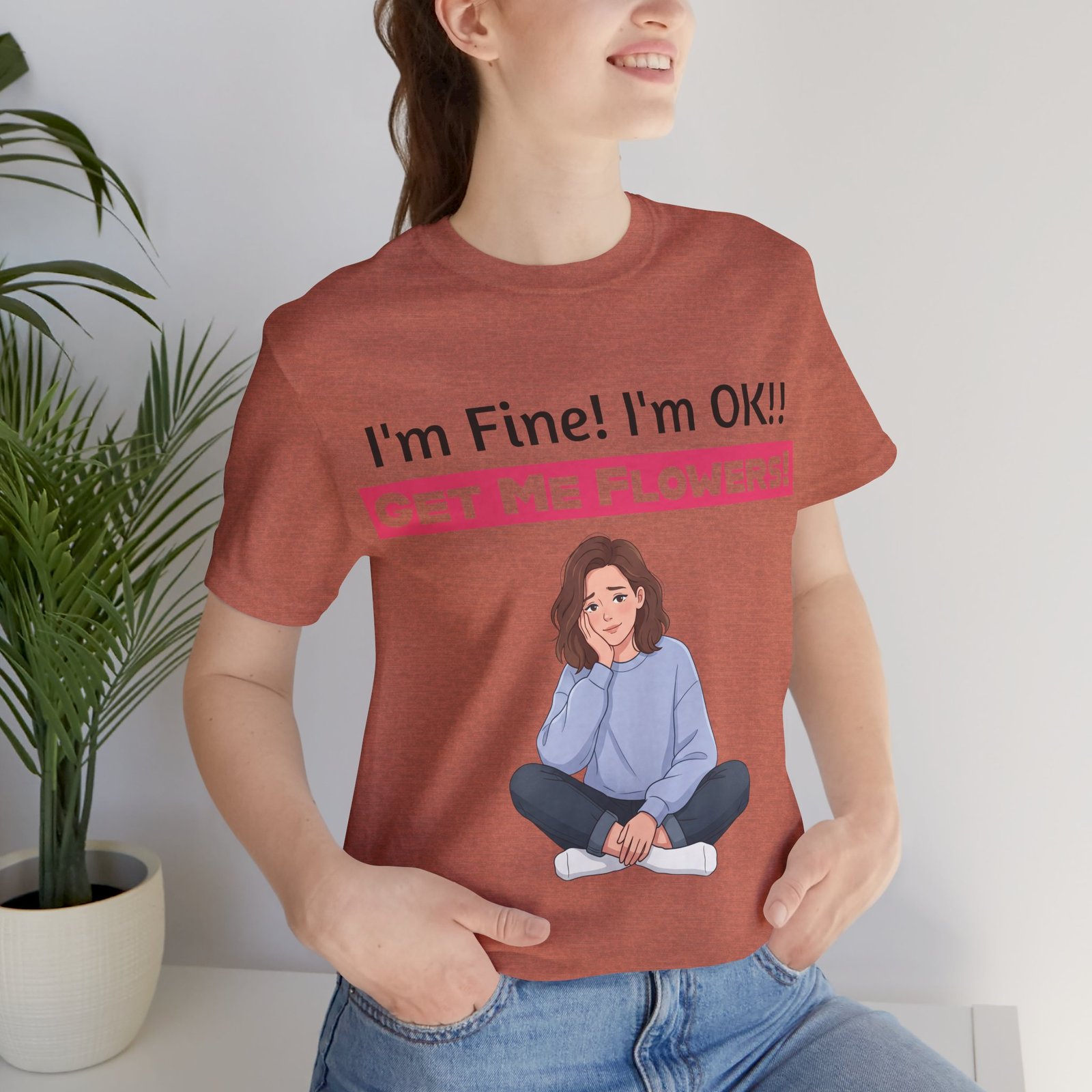 Rust-colored t-shirt featuring a funny graphic of a seated woman and the text I'm Fine! I'm OK!! Get Me Flowers!