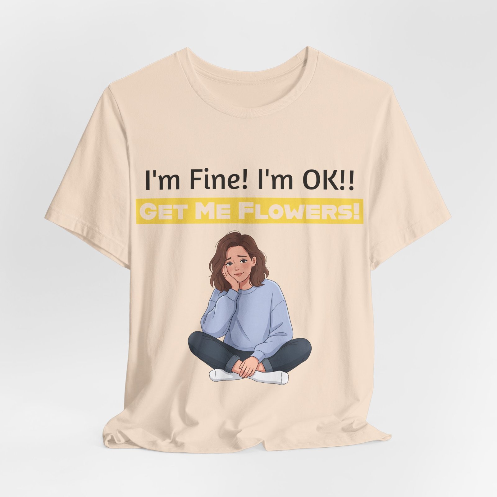 Tan t-shirt featuring a cartoon woman sitting cross-legged and the text "I'm Fine! I'm OK!! GET ME FLOWERS!"