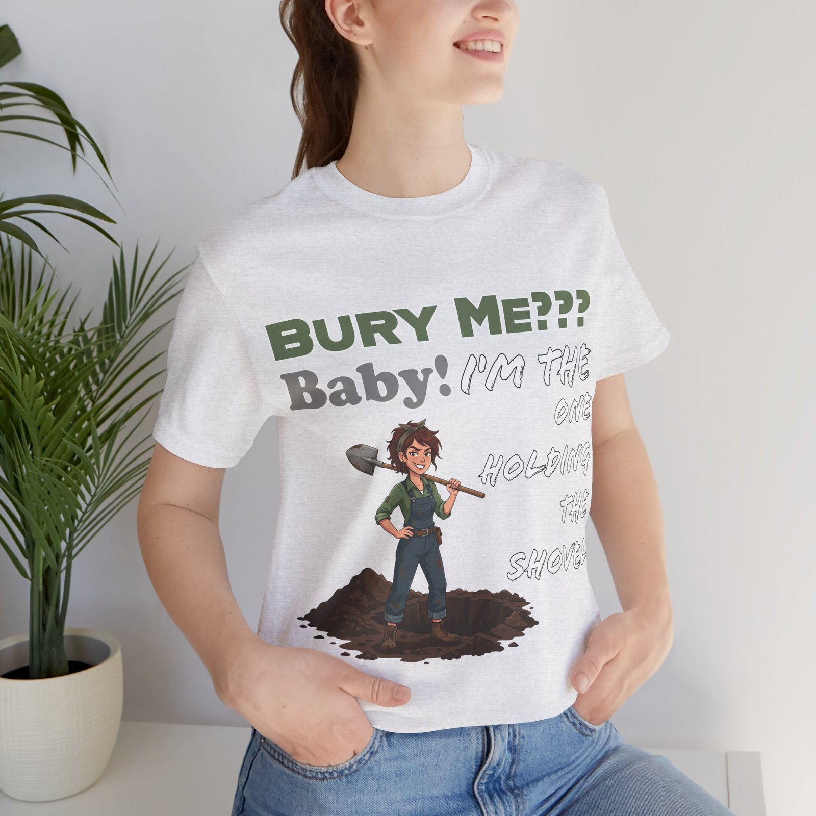 White t-shirt featuring an illustrated character holding a shovel and text that reads "Bury Me??? Baby! I'm the One Holding the Shovel"