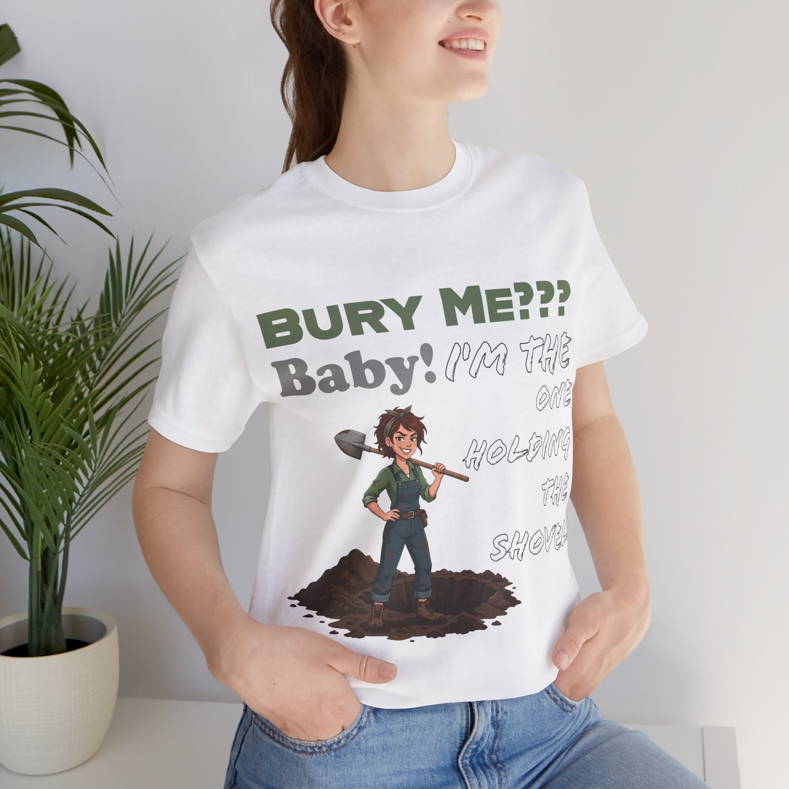 White t-shirt featuring an illustration of a woman with a shovel and the text "Bury Me??? Baby! I'm the One Holding the Shovel"
