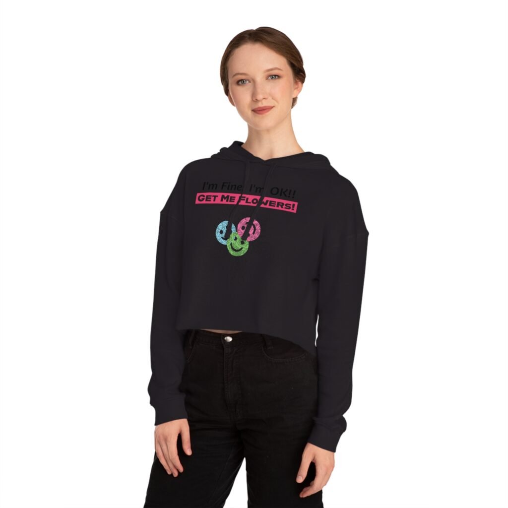 Woman wearing a black cropped hoodie with "I'm Fine! I'm OK!! GET ME FLOWERS!" pink text and colorful flower graphic.