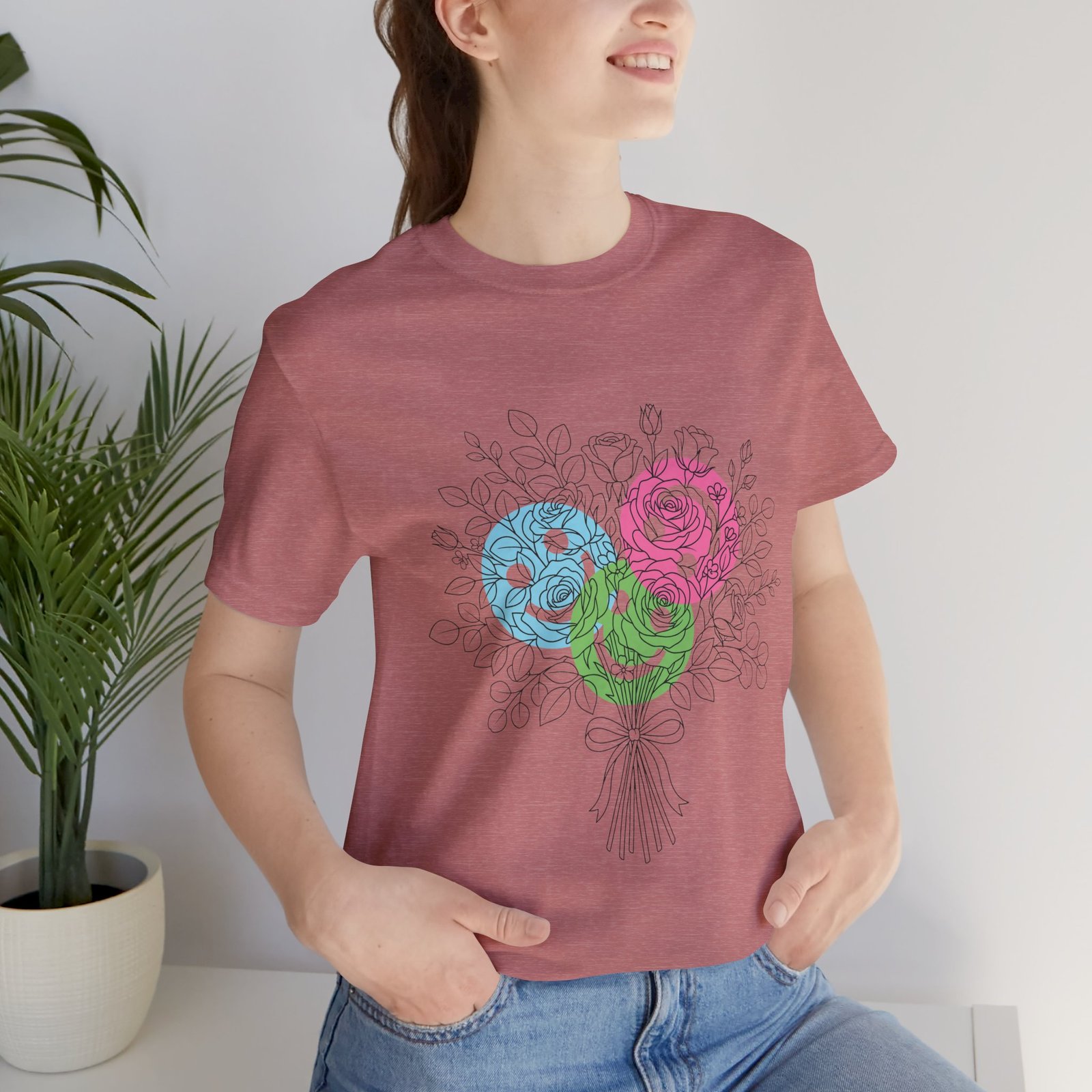 Woman wearing a dusty rose T-shirt featuring a hand-drawn floral bouquet with teal, magenta, and lime spiral blooms.
