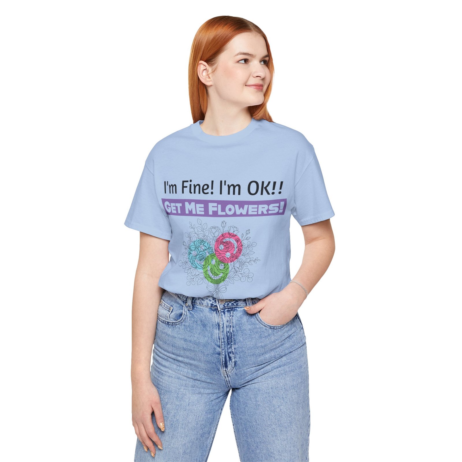 Woman wearing a light blue graphic t-shirt with 'I'm Fine! I'm OK!! GET ME FLOWERS!' and colorful floral sketches.