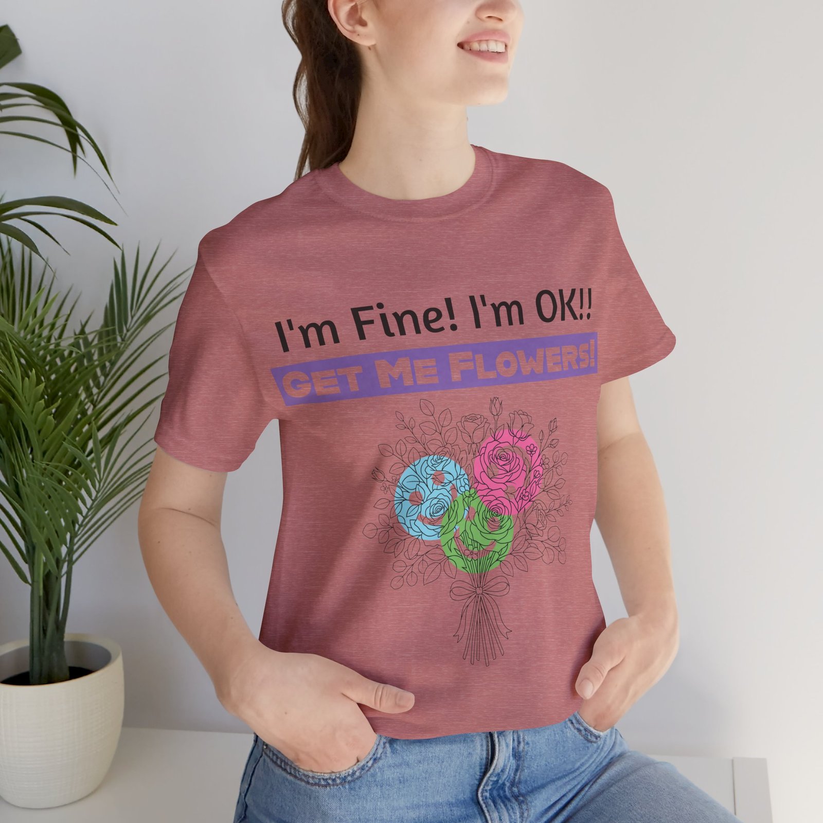 Woman wearing a mauve sarcastic floral t-shirt with the text "I'm Fine! I'm OK!! GET ME FLOWERS!" and colorful flower art.