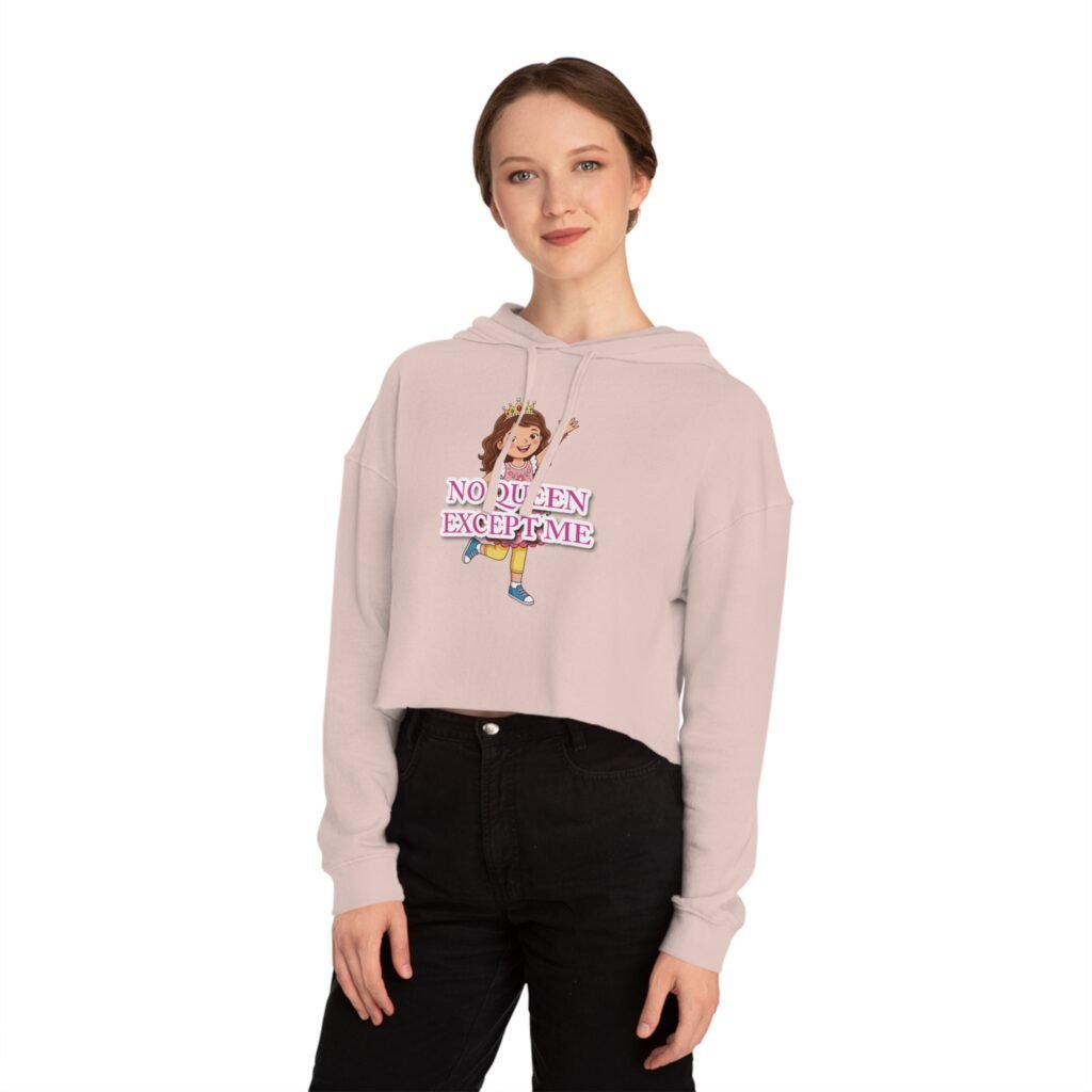 Woman wearing a pale pink cropped hoodie featuring a 'No Queen Except Me' cartoon graphic and black high-rise jeans.