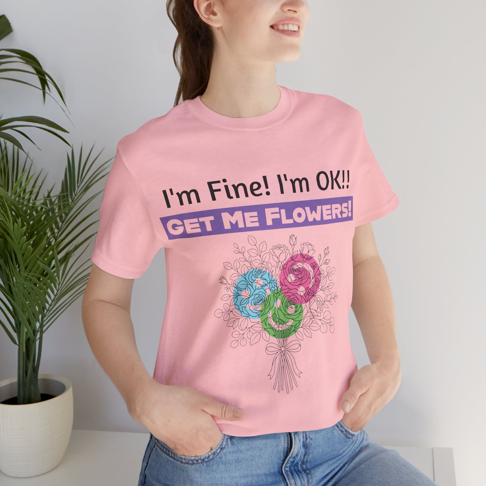 Woman wearing a pink funny sarcastic T-shirt with floral graphic and text I'm Fine! I'm OK!! Get Me Flowers!