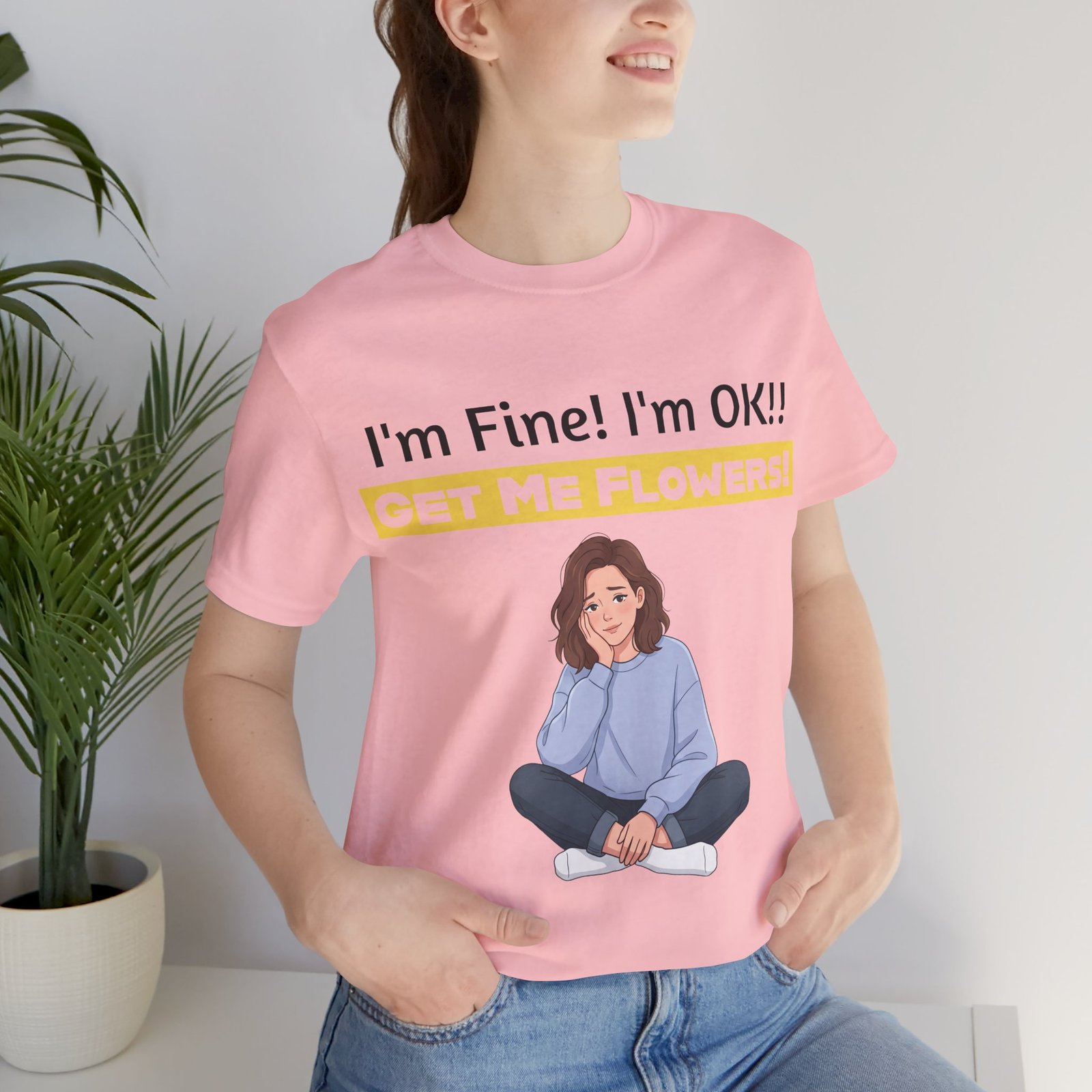 Woman wearing a pink 'I'm Fine! I'm OK!! Get Me Flowers!' funny T-shirt with a cartoon illustration.