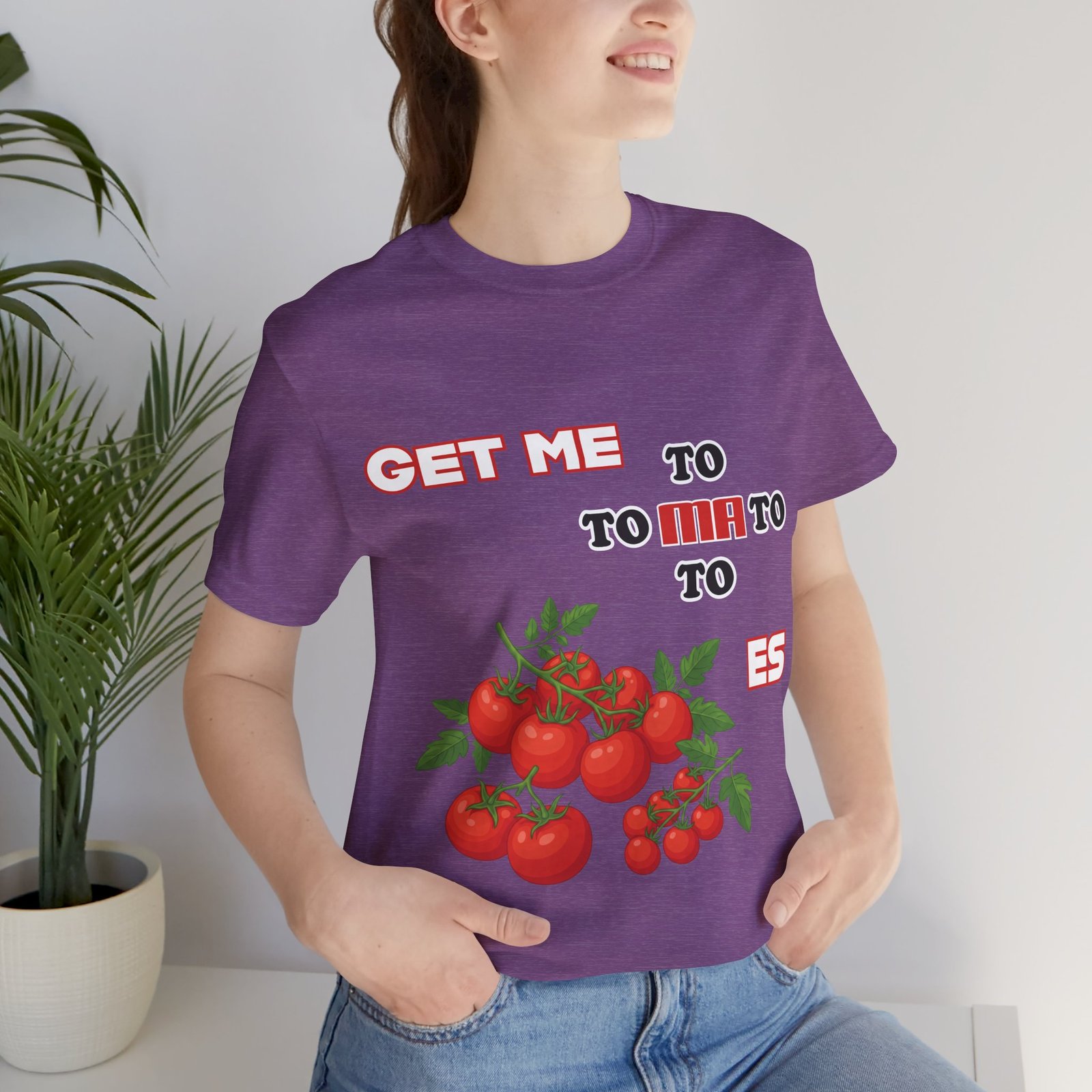 Woman wearing a purple crew neck t-shirt featuring the text "GET ME TO MA TO TOES" and illustrated tomato clusters.