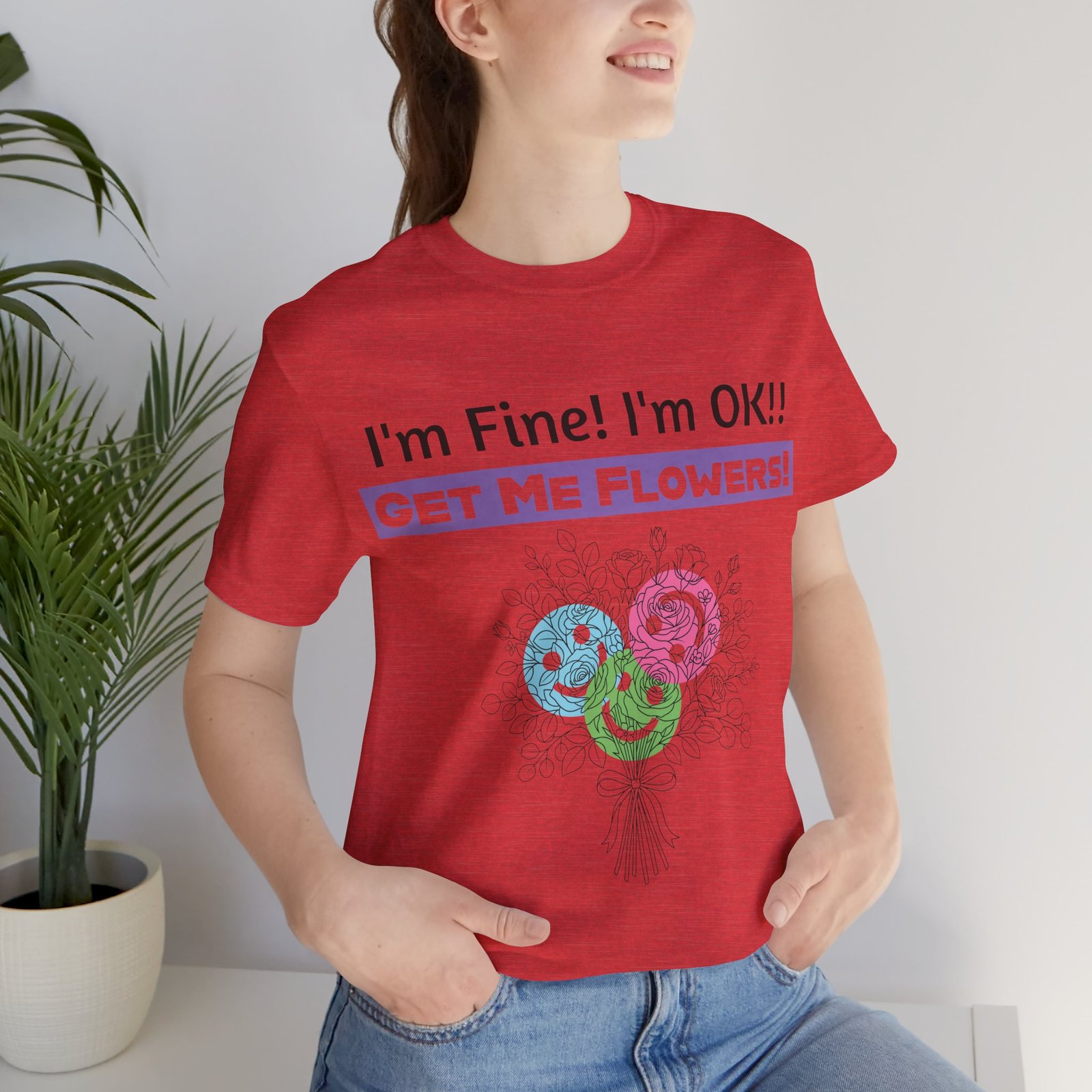 Woman wearing a red graphic t-shirt that says "I'm Fine! I'm OK!! GET ME FLOWERS!" with a colorful floral bouquet print.