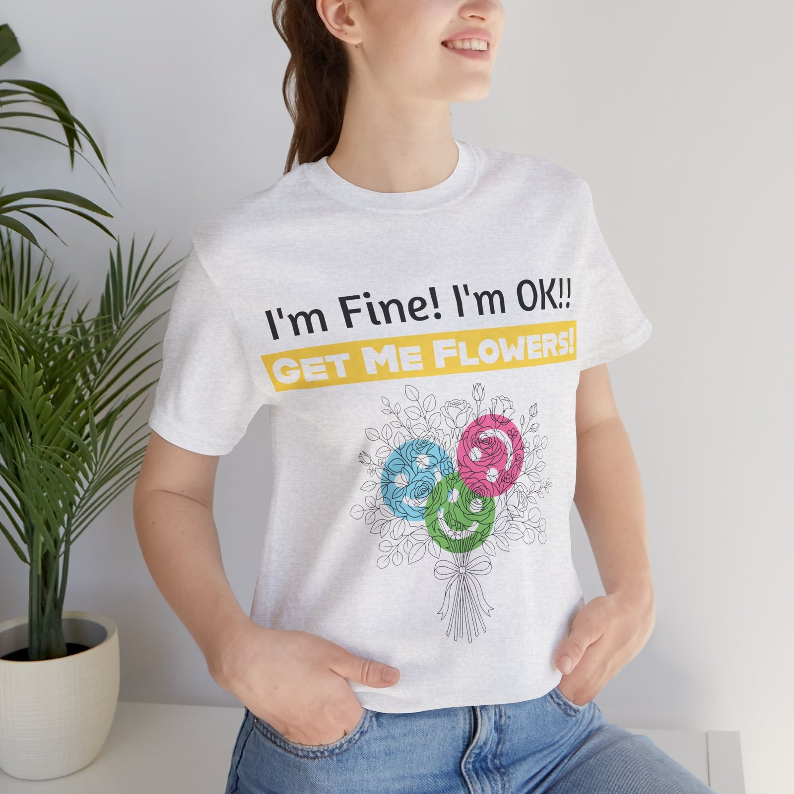 Woman wearing a white cotton crew-neck t-shirt with 'I'm Fine! I'm OK!! GET ME FLOWERS!' text and abstract flower graphic