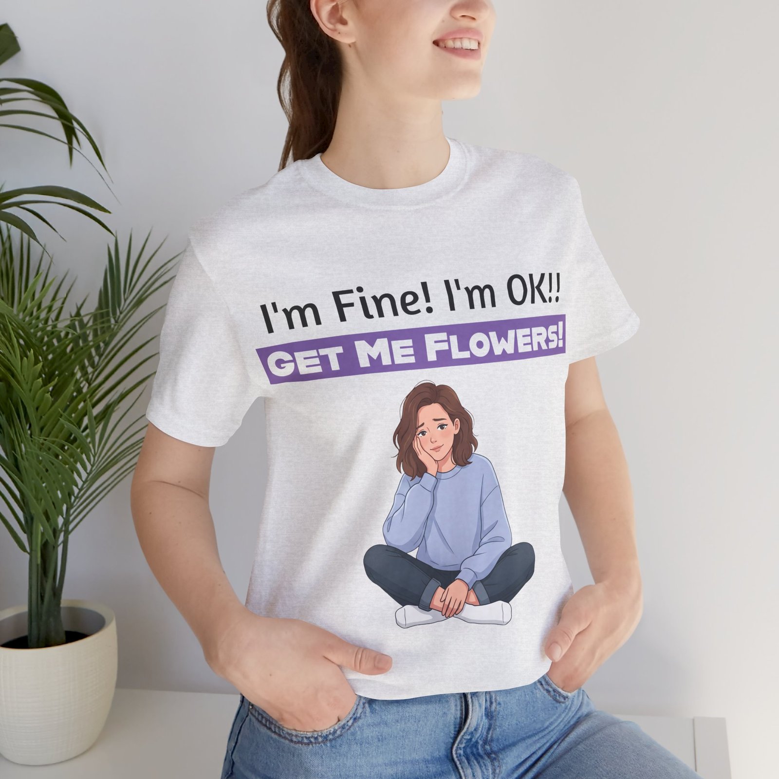 Woman wearing a white t-shirt with 'I'm Fine! I'm OK!! GET ME FLOWERS!' text and a cartoon girl illustration.