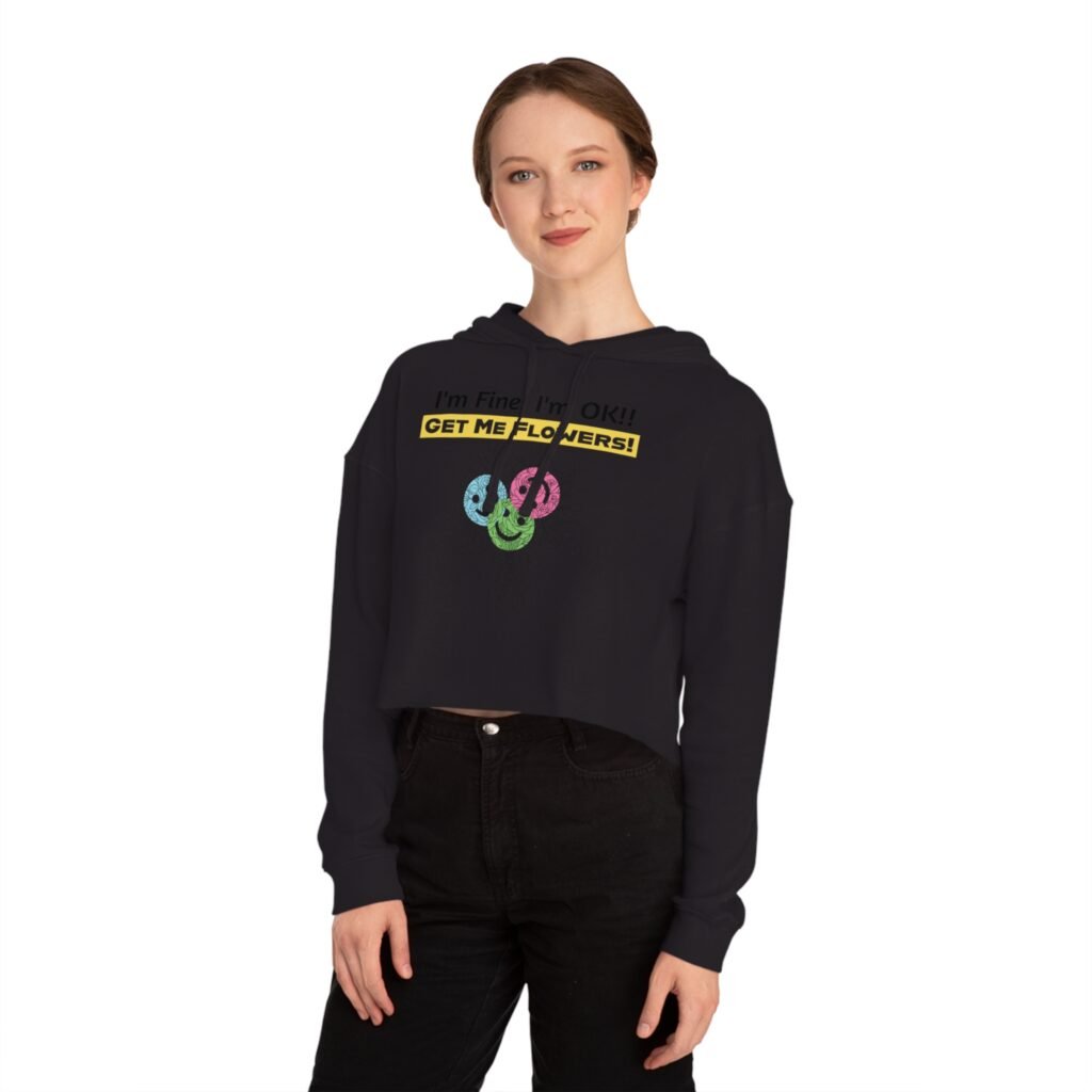 Woman wearing black cropped hoodie with 'I'm Fine! I'm OK!! GET ME FLOWERS!' yellow text and colorful floral graphic.