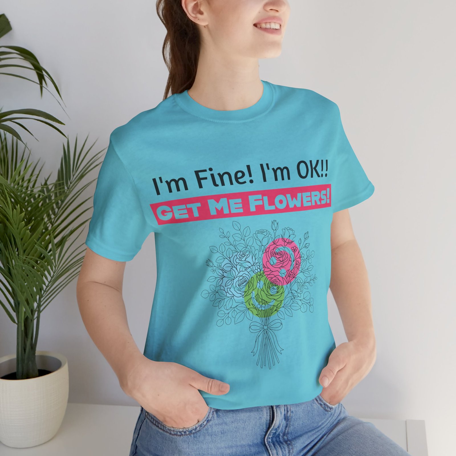 Woman wearing light blue t-shirt with "I'm Fine! I'm OK!! Get Me Flowers!" text and floral bouquet graphic.