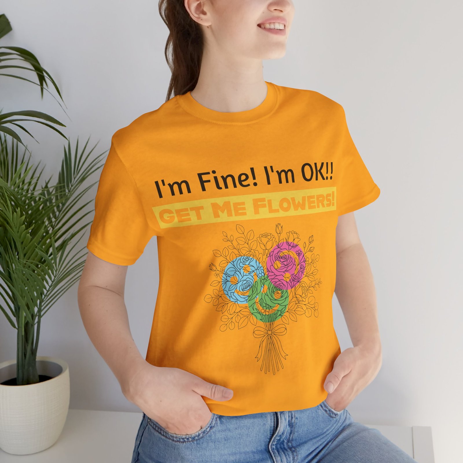Woman wearing orange Funny T-Shirt "I'm Fine! I'm OK!! Get Me Flowers!" with colorful floral graphic.